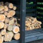 Black log store with two compartments with logs in one and split logs in other