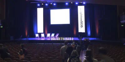 Brighton SEO 2015 at the Brighton Dome showing the stage, 5 deckchairs and the Brighton SEO illuminated letters on the lip of the stage.