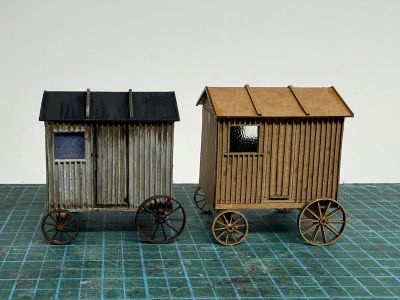Side view of the original shepherds hut model on left painted weathered grey and on the right is the new version unpainted.