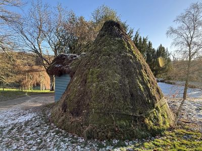 Scotney Castle ice house - a conical heather cover brick vault with sky blue wooden porch and heather roof providing access. Ice taken from the lake could be kept here for a year or more.
